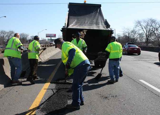 Five workers patching potholes on the highway